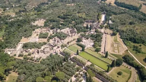 An aerial view of Villa Adriana showcasing expansive Roman ruins with various structures gardens and pools surrounded by greenery