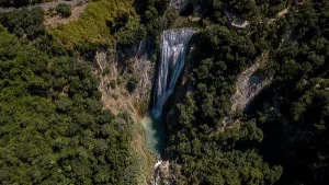 A wide cascading waterfall with lush greenery surrounding it known as the Aniene Waterfall in Tivoli Italy