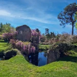 Iconic view of the Garden of Ninfa with river and tower ruins