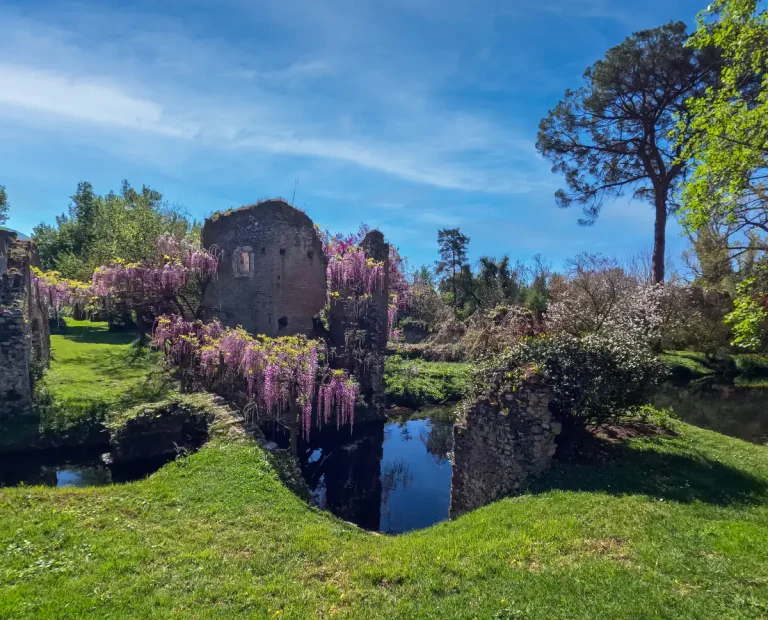 Iconic view of the Garden of Ninfa with river and tower ruins