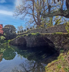 Scenic view of the Garden of Ninfa with bridge, river, and trees