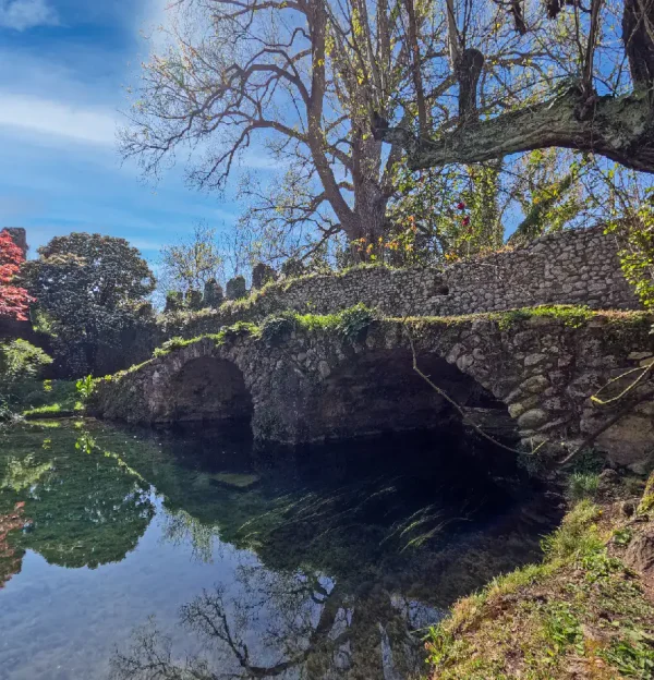 Scenic view of the Garden of Ninfa with bridge, river, and trees