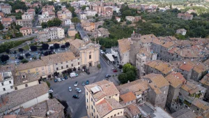 Drone view of the center of Bagnaia Viterbo featuring the main church and a tall tower surrounded by historic buildings