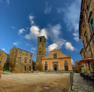 Church of San Donato in Civita di Bagnoregio Scoot around Rome Piazza San Donato in Civita di Bagnoregio featuring the Church of San Donato with its tall bell tower surrounded by historic stone buildings under a partly cloudy sky