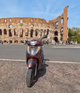 Scooter Guided Tour Colosseum Views and Roman Adventures Scoot around Rome Scooter parked with a perfect view of the Colosseum in Rome highlighting the unique experience of our scooter guided tours