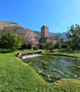 Iconic view of the Garden of Ninfa with river and tower ruins