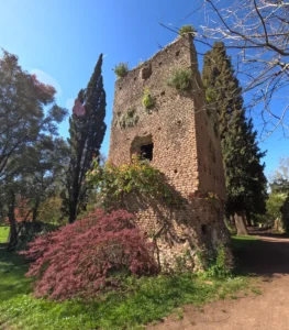 Iconic view of the Garden of Ninfa with river and tower ruins