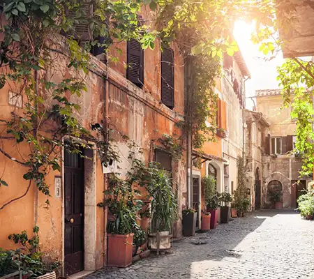 Peaceful cobblestone street in Rome with ivy covered buildings in the morning light